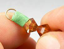 Bicone beads on a head pin with green clay wrapped around wire